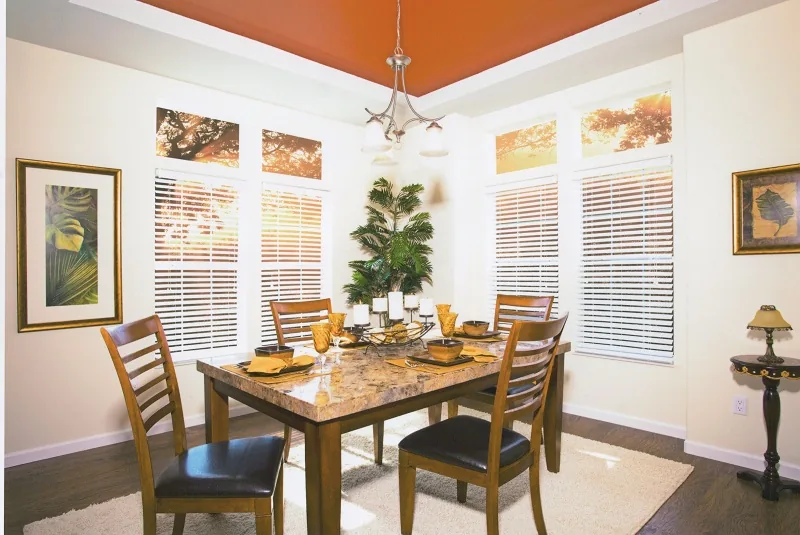 Dining room with a wood table set for six beneath a painted ceiling