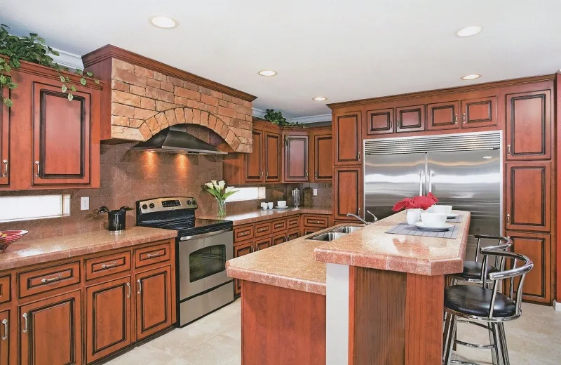Cherry-wood kitchen with stainless appliances, brick-look range hood and a large island
